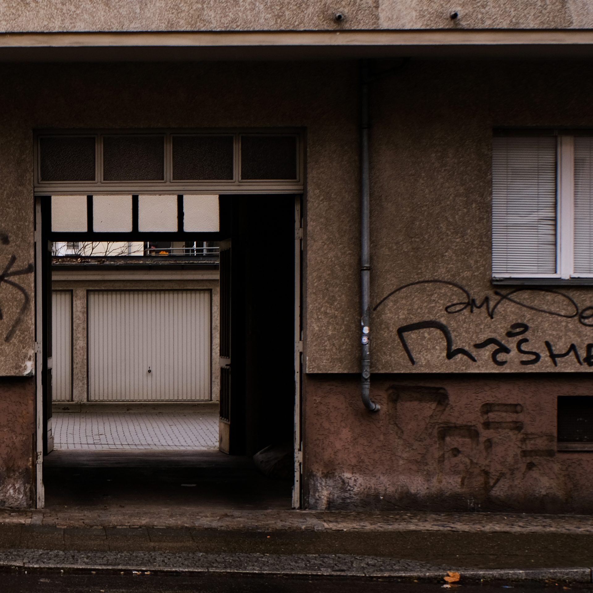 Doorway, brown plastered wall, drawn blinds with a small chink. Braun verputzte Wand, Hoftor und heruntergelassene Jalousie mit kleinem Knick